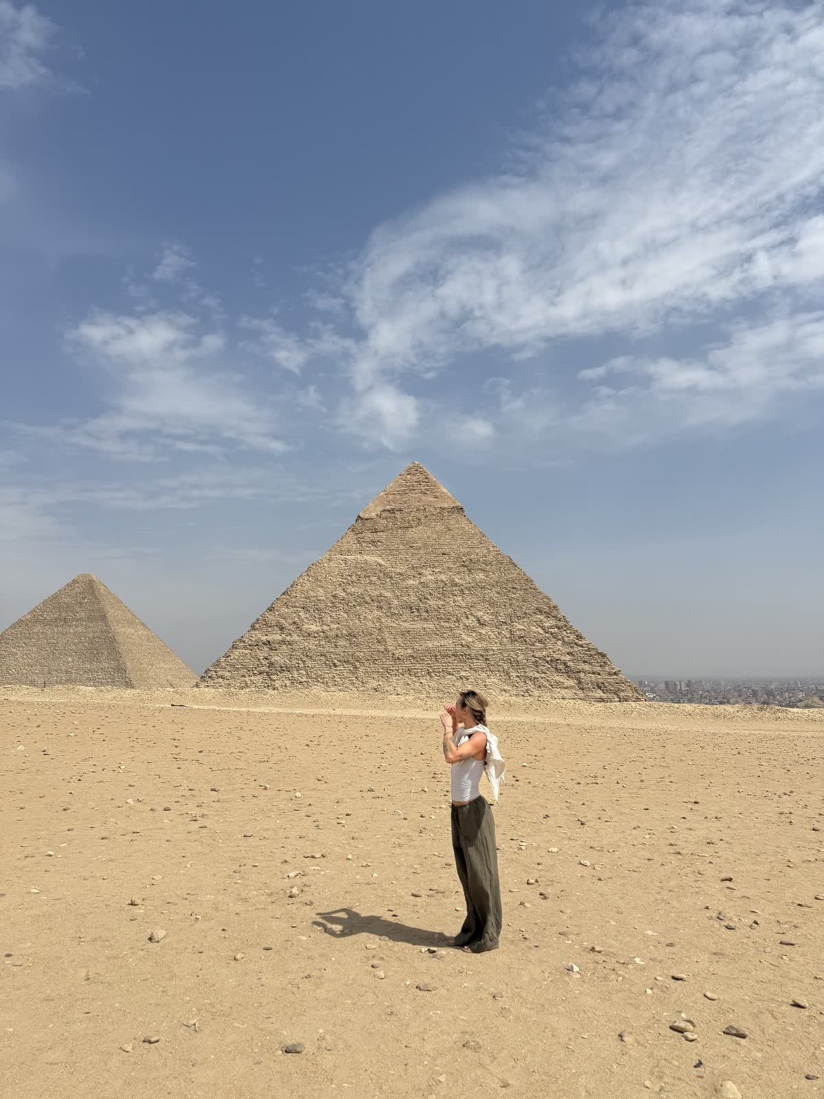 A woman photographs the pyramids from the open sand of the Giza plateau