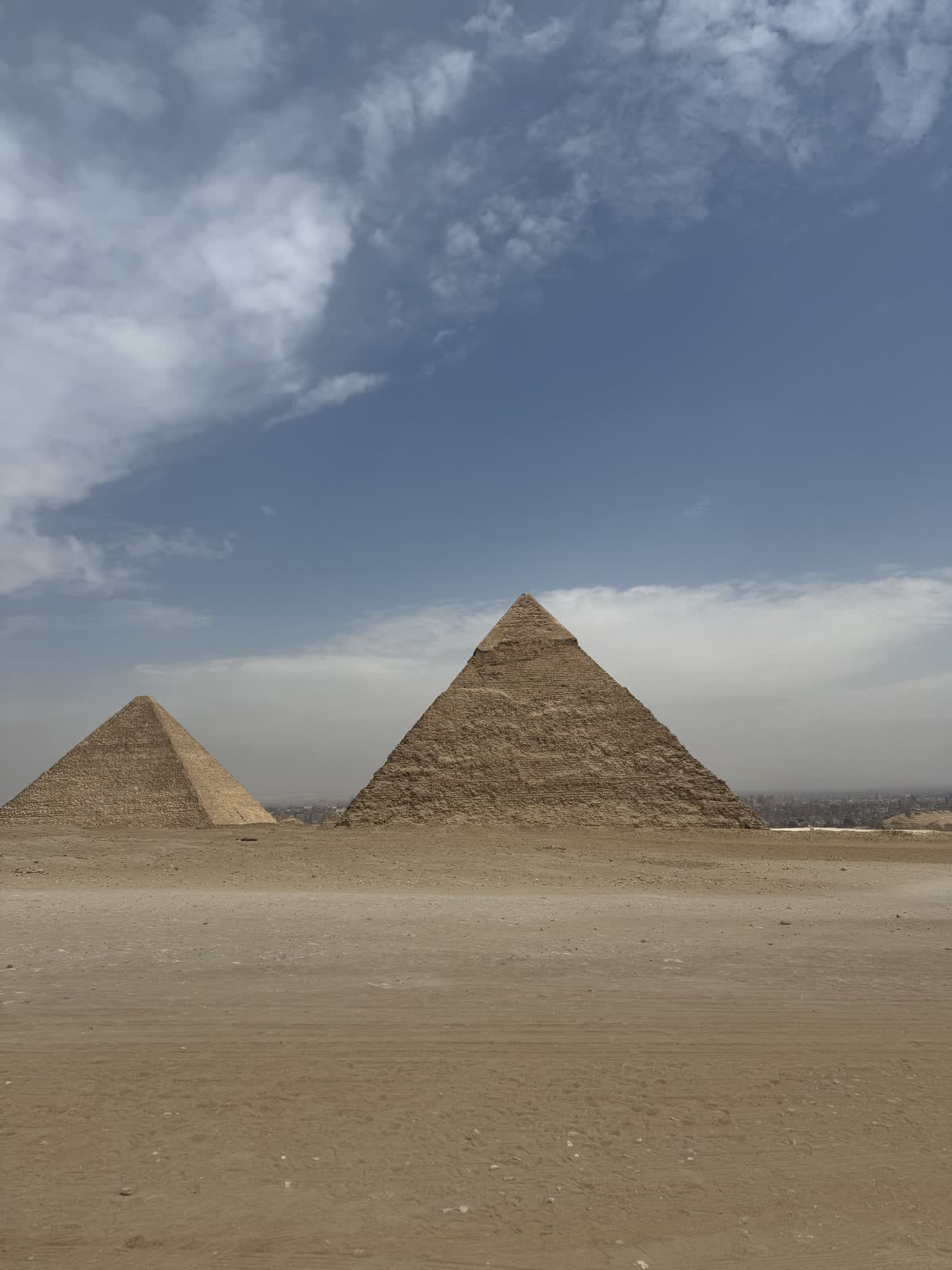 Two of the pyramids of Giza under a wide blue sky