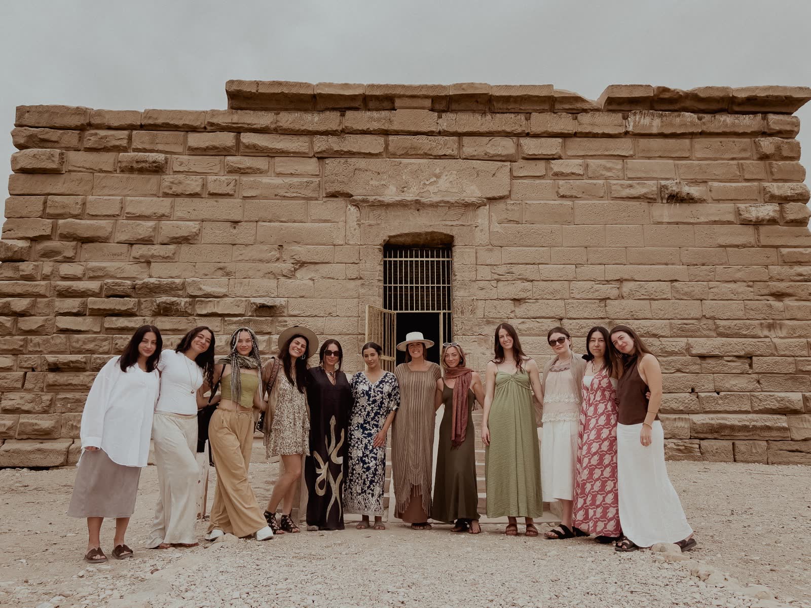 Twelve women standing together in front of a sandstone temple